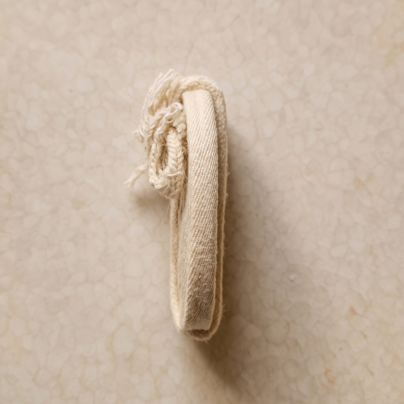 A coiled Parsi Kasti seen from the side, showing its flat woven width