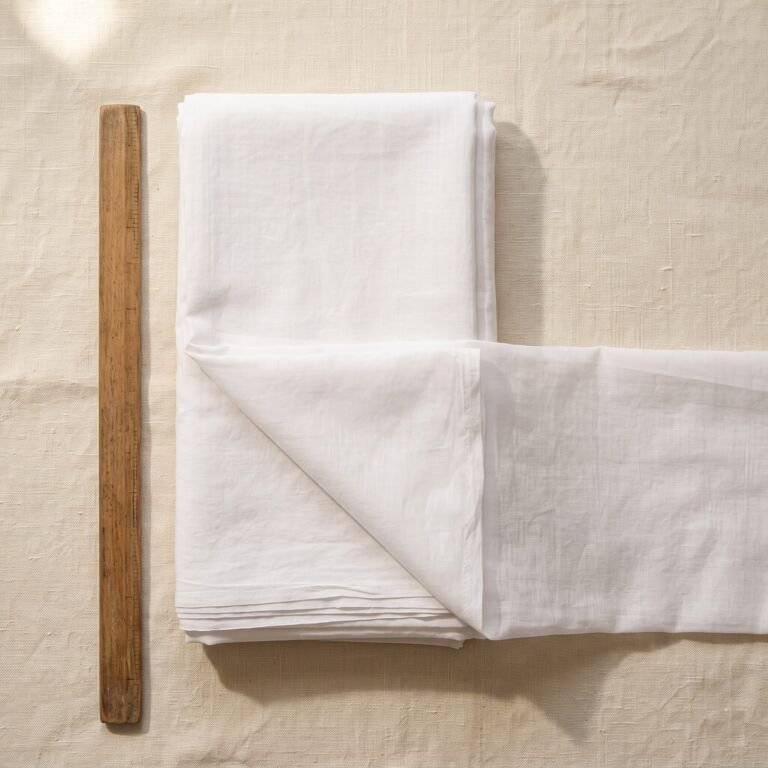 Folded white Maal-maal cloth beside a wooden ruler