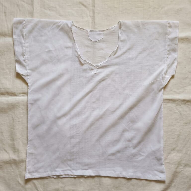 A white Parsi Sadra with short sleeves laid flat