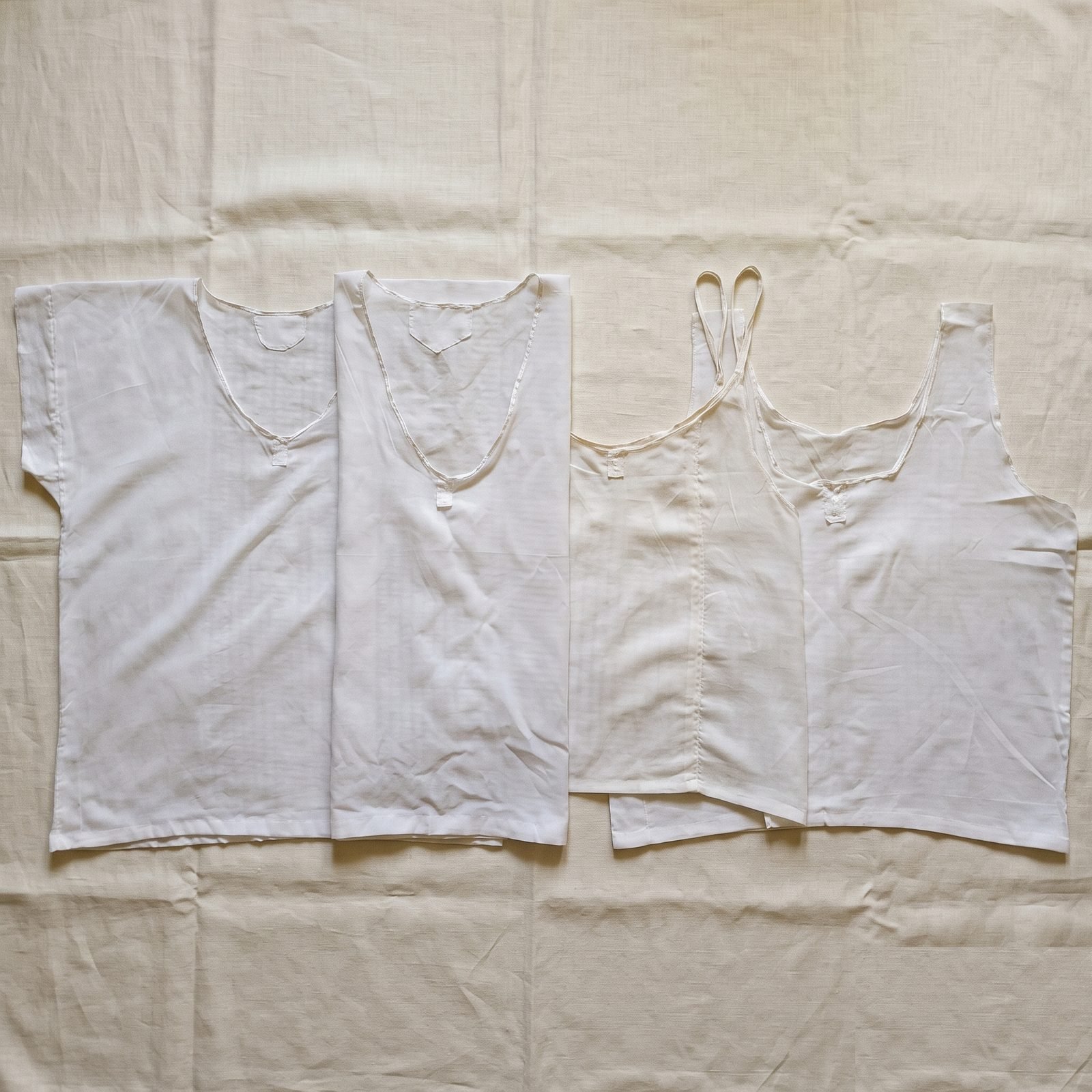 Four Parsi Sadras laid side by side: with sleeves, sleeveless and with straps