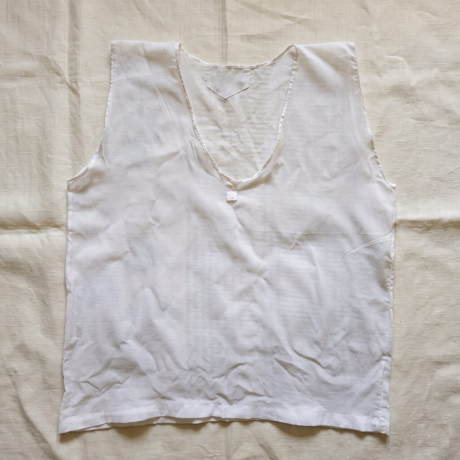 A sleeveless white Parsi Sadra laid flat